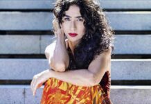 Marisa Monte's 10 favorite Brazilian songs: The Brazilian music star poses in a orange and yellow flame dress againsta wooden background