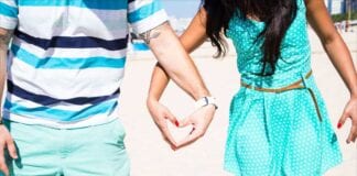 couple holding heart-shaped hand on beach