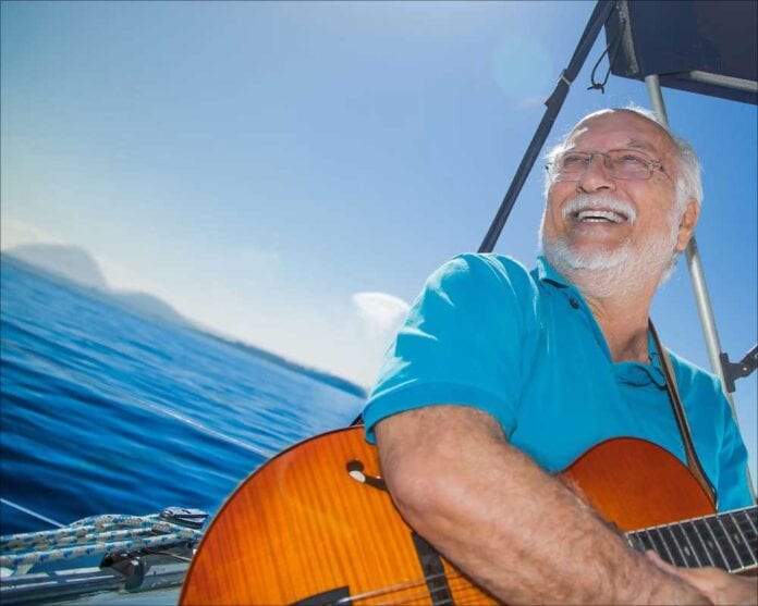 Brazilian musician Roberto Menescal holding guitar in boat