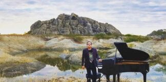 Brazilian pianist Ricardo Bacelar standing nest to grand paino in Ceara Brazil