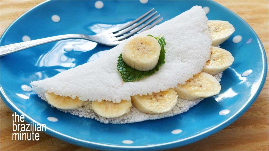 Blue dinner plate holds a tapioca crepe filled with banana slices.. A snack from the Indigenous peoples of Brazil.