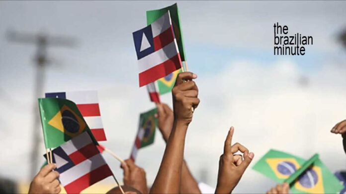 Celebrating Bahia's Independence Day with handheld flags for the state of Bahia and of Brazil.