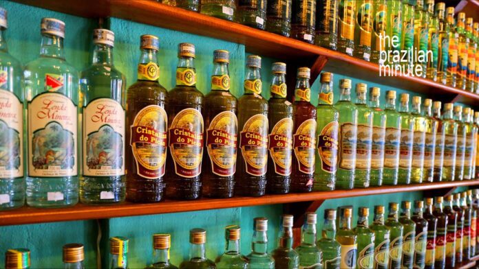 Brazilian Cachaça Explained: Dozens of cachaça bottles from various distillers line the wooden shelves, side by side.