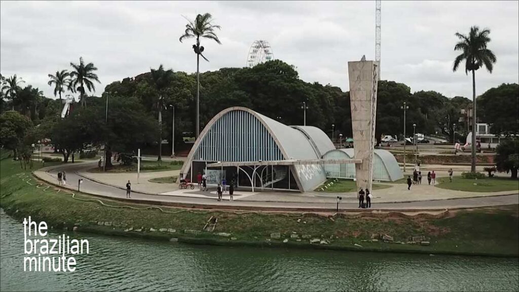 Understanding Brazilian Architect Oscar Niemeyer: His Modernist arching design of the Igreja de Sao Francisco de Assis, Belo Horizonte. with paln trees and stone shoreline.