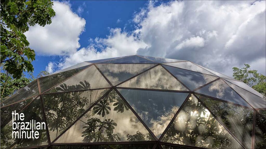 Inhotim Is Brazil's outdoor artistic masterpiece. Palm trees, blueskies and puffy-whie clouds are reflected in the triangular glass panes of a geodesic dome.