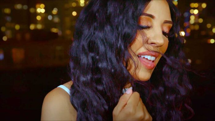 Cecy Santana's video and lyrics capture Sao Paulo's positivity. Brazilian singer performing in front of gold-hued city lights at night.