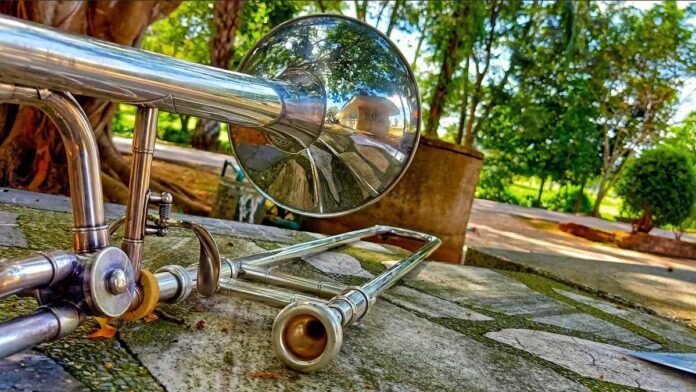 Roy Stephansen's musical move. Silver trombone sits on a stone bench surrounded by park-like greenery.