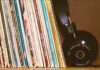 Record collection of 12 Influential Brazilian Jazz Albums on a wood shelf with black headphones leansing against them.