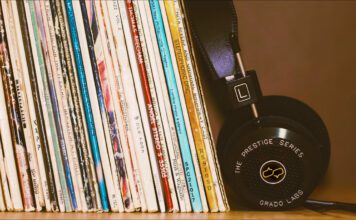 Record collection of 12 Influential Brazilian Jazz Albums on a wood shelf with black headphones leansing against them.