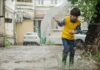 The Waters of March 50th Anniversary The Waters of March 50th Anniversary. A Young boy plays in a rain puddle while holing a small umbrella.